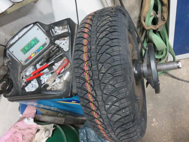 PKW Reifen aufgespannt auf der Wuchtmaschine mit den Wuchtgewichten.